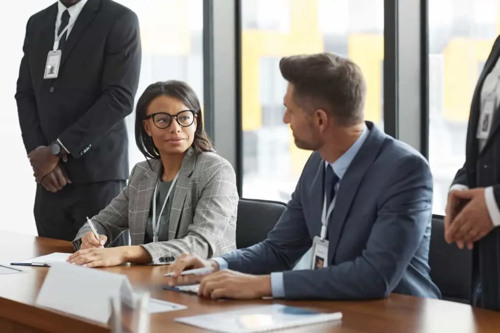 Professionals in suits talking during formal business conference with name badges.